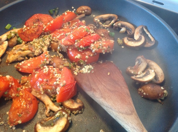 Stirring in the hemp seeds through the tomato-mushroom mix